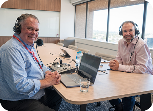 chris nelder and marc england sitting at a desk with podcast equipment