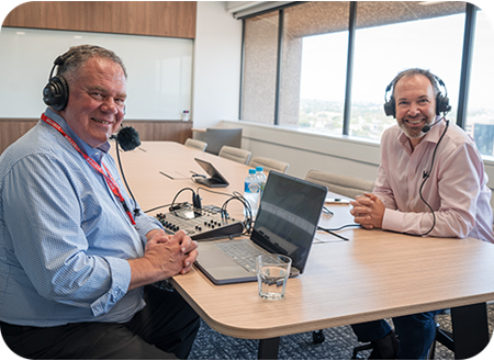chris nelder and marc england sitting at a desk with podcast equipment